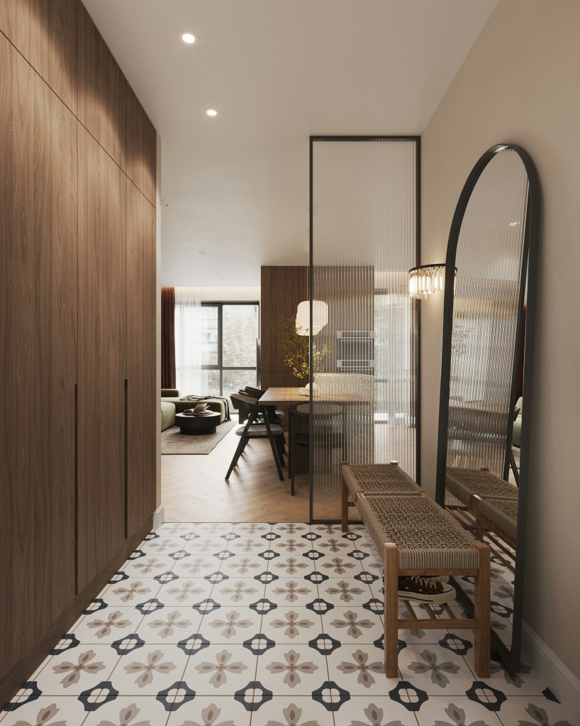 Intérieur moderne d'entrée avec un sol carrelé fleuri, des murs en bois, un banc en bois, un miroir en arc et une lumière sur un meuble, menant vers un espace de vie lumineux.